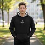 Man wearing a black hoodie with a logo in an outdoor setting