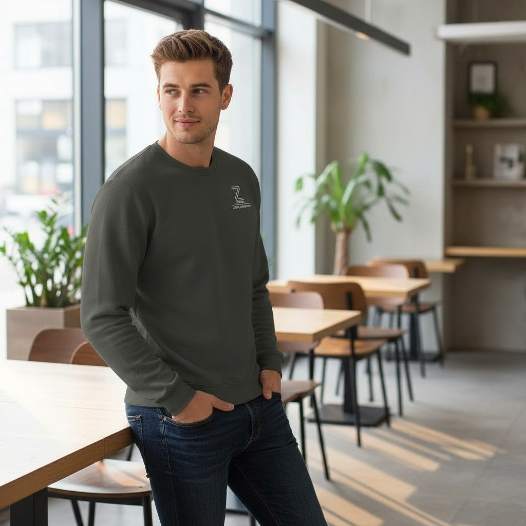 Man wearing a dark gray sweatshirt with a logo in a modern cafe setting