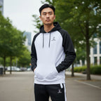 Man wearing a black and white hoodie with a brand logo, standing outdoors.