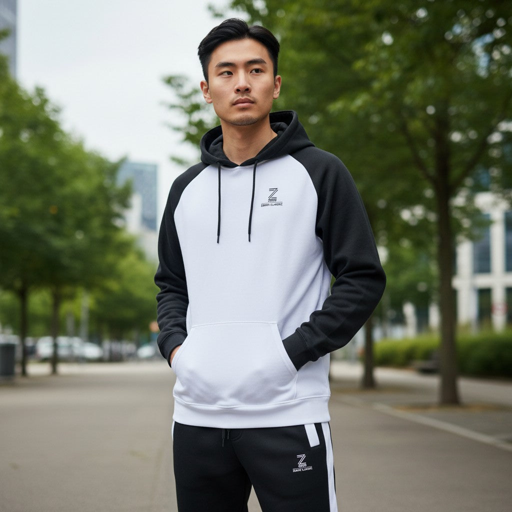 Man wearing a black and white hoodie with a brand logo, standing outdoors.