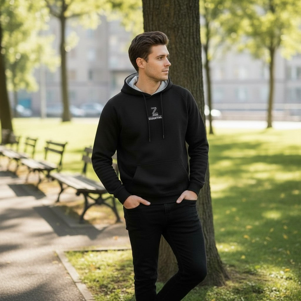 Man wearing a black hoodie with a logo in a park