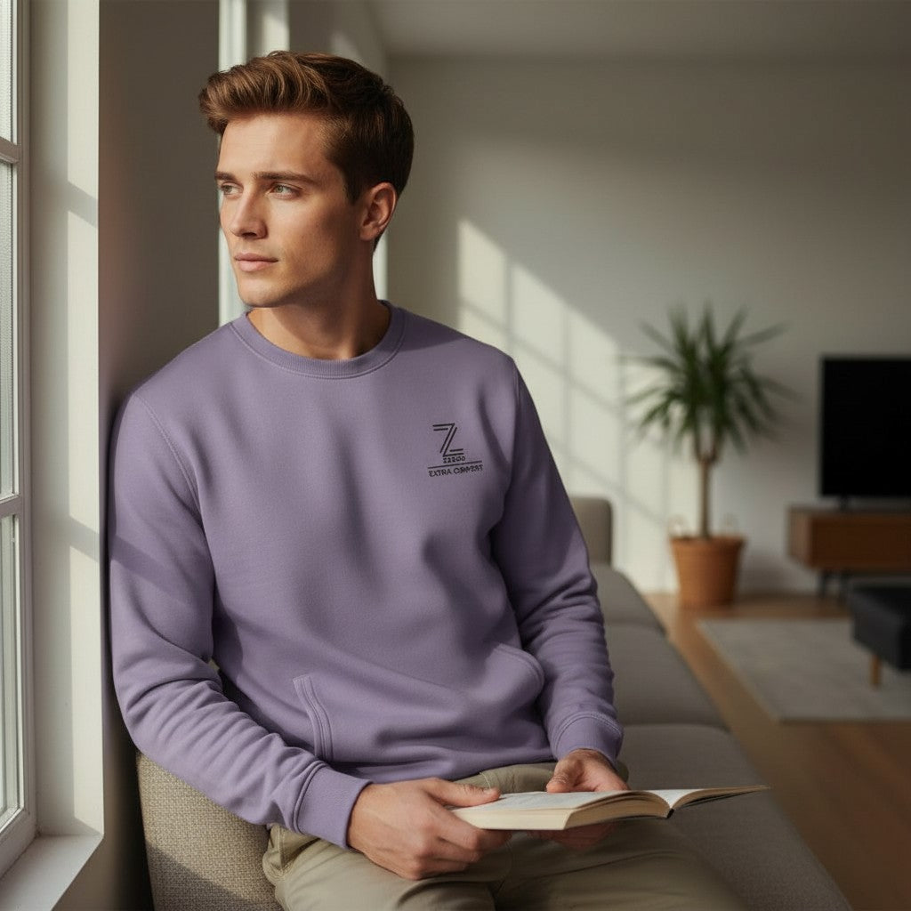 Man in a purple sweatshirt reading a book in a cozy living room.