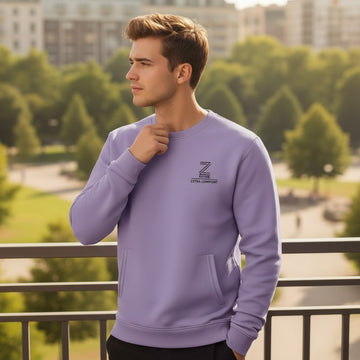 Man wearing a purple sweatshirt with a logo, standing outdoors with trees and buildings in the background